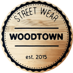 Circular logo with a wood grain texture background, featuring bold black text that reads 'STREET WEAR' arched along the top, 'WOODTOWN' centered in large block letters, and 'est. 2015' at the bottom, all enclosed within a black scalloped border with dotted inner lines.